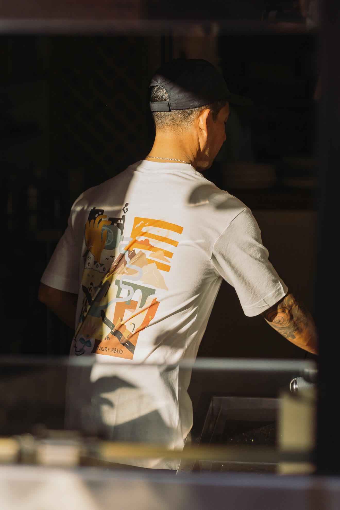 A man wearing an Angry Pablo t-shirt in low light
