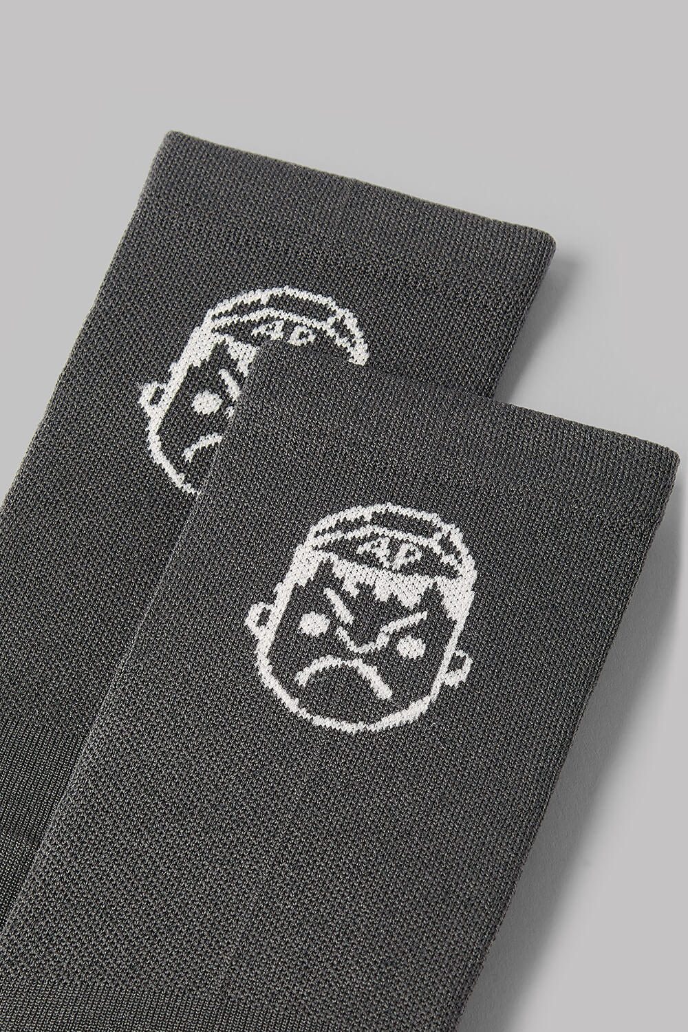 Two gray socks with white face designs on a light gray background