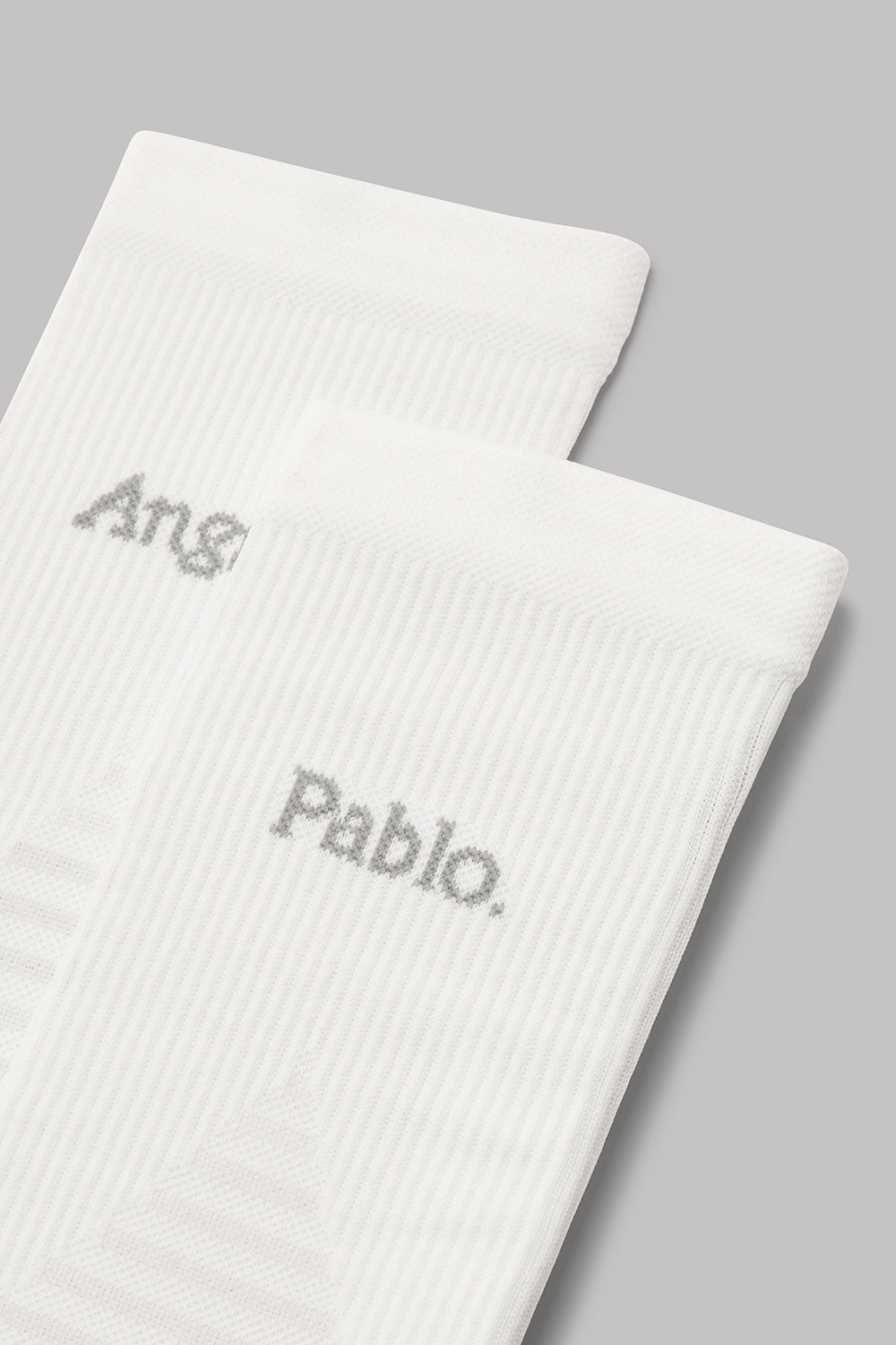 Two white socks with embroidered names on a gray background